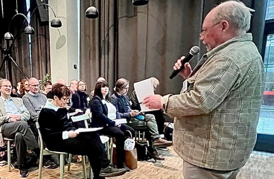 En man i kavaj talar i mikrofon.