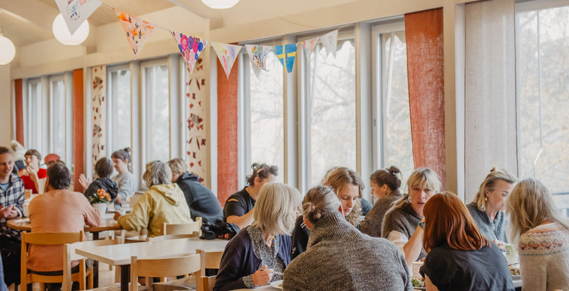 Folkhögskoledeltagare vid matborden i en matsal.