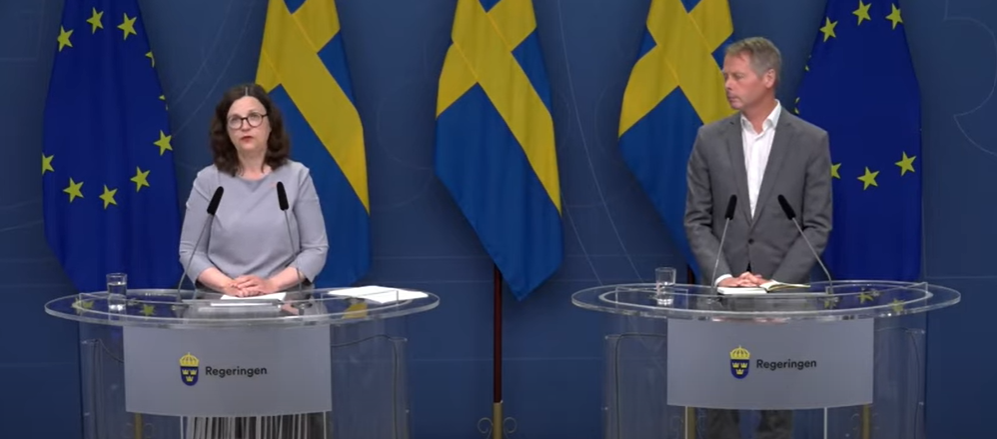 Kvinna och man står vid talarstolar och mikrofoner.