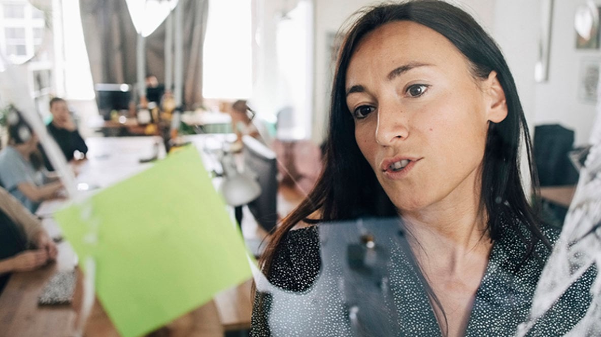 En kvinna skriver på en gul post-it.