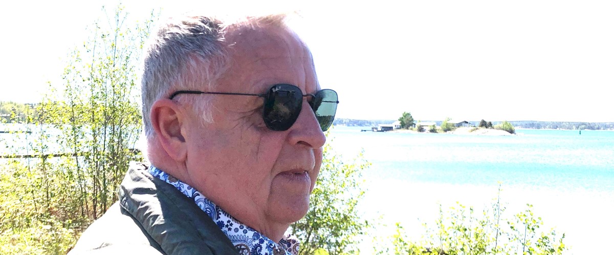 Man med solglasögon står vid havet.