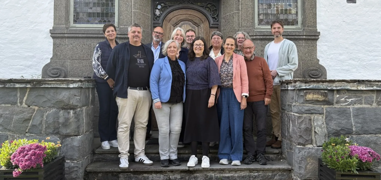 En grupp människor utomhus på en trappa framför en skolbyggnad.