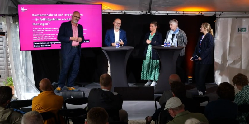Fem personer står på en scen framför en publik.