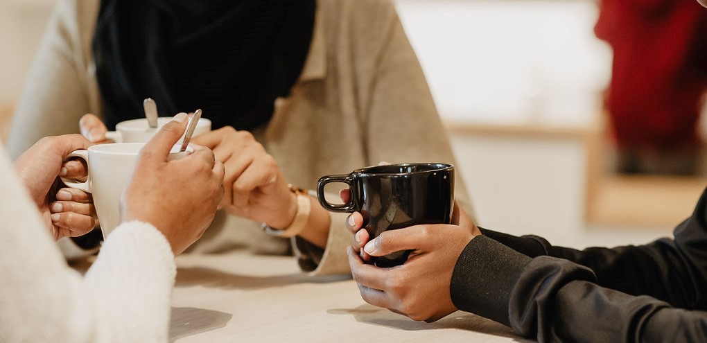 Händer som håller i kaffekoppar.