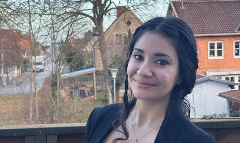 En kvinna ler och tittar in i kameran. 