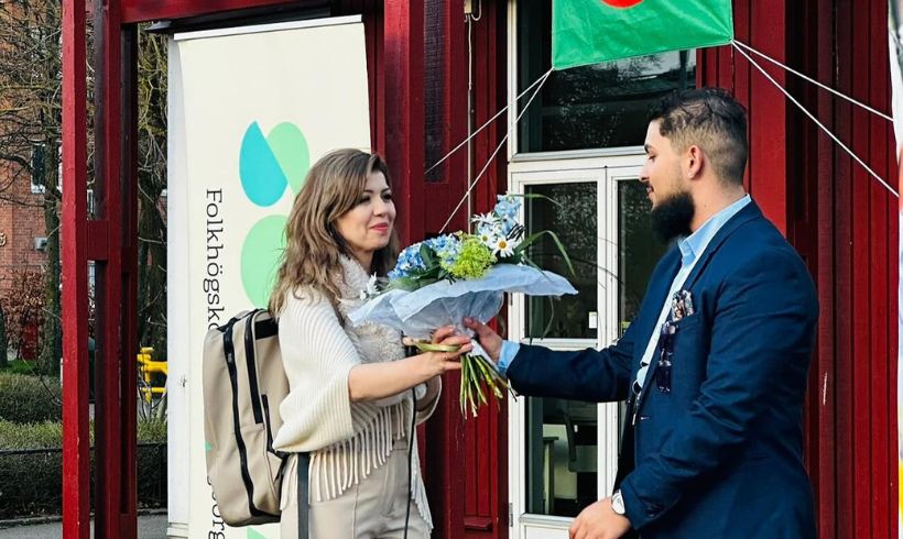 Midia Osman Taha tar emot blommor av en man på en scen.